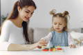 Parent guiding a child using a Montessori activity board to match shapes