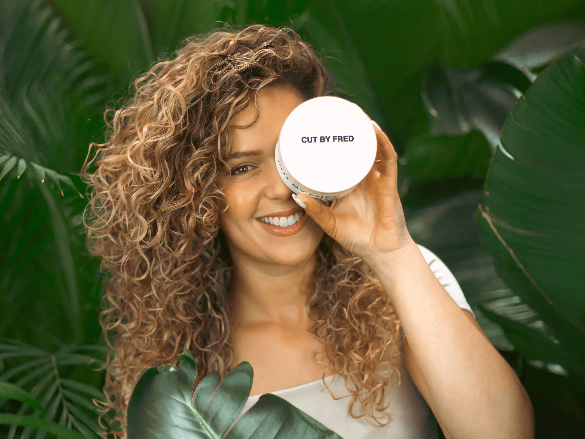 Femme au cheveux bouclés avec un masque dans la main