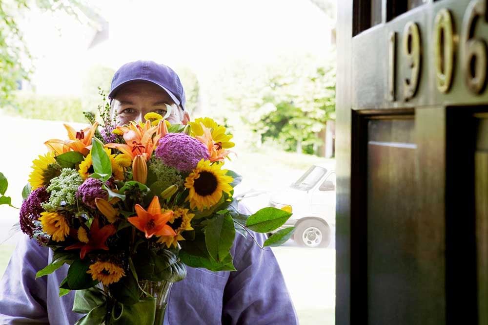 Picture of a gentleman in uniform delivering a bouquet of flowers to a home