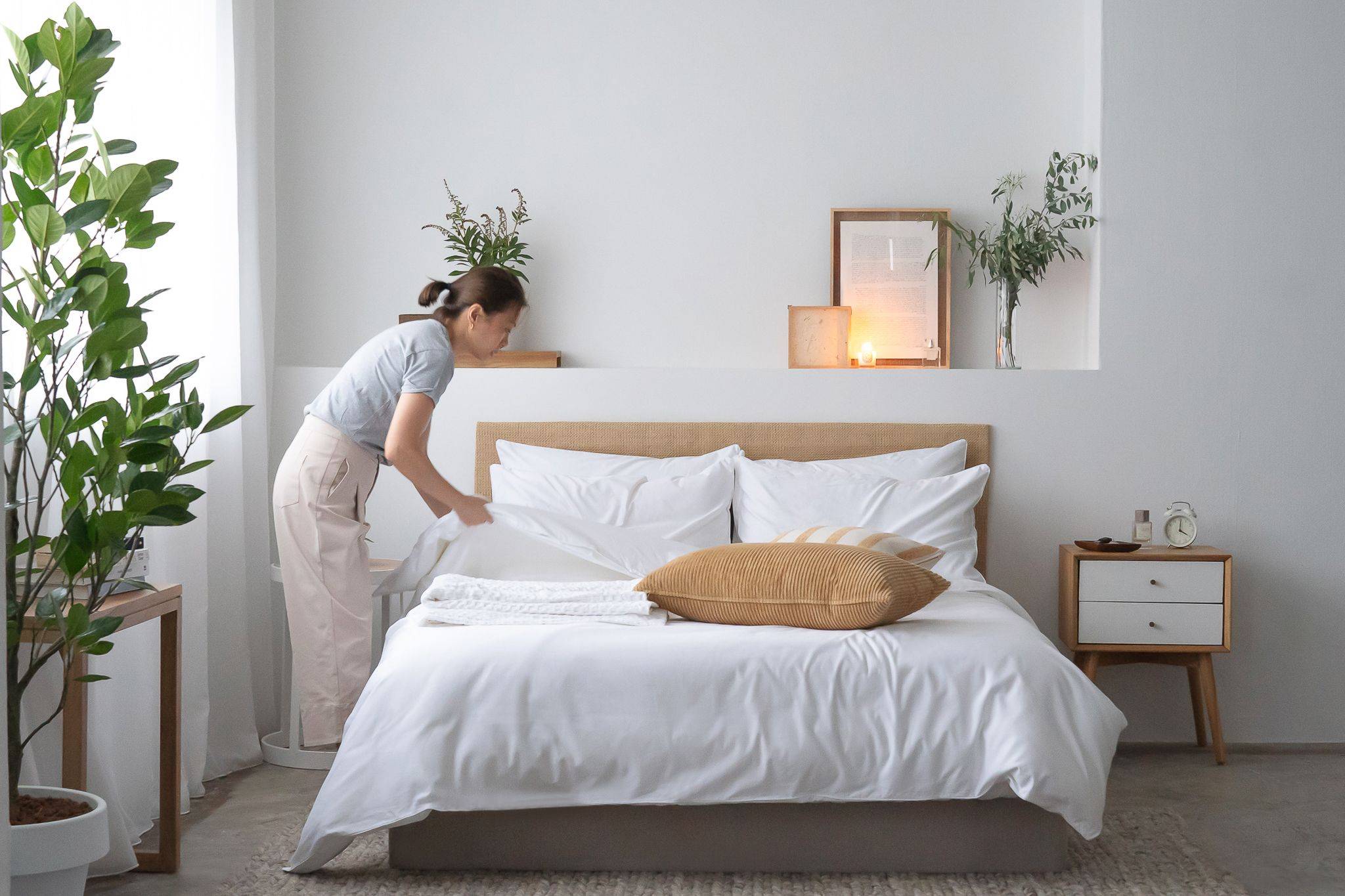 Woman making bed with Weavve's white cotton bed sheets