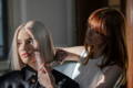 blonde woman getting hair cut by a woman with red hair