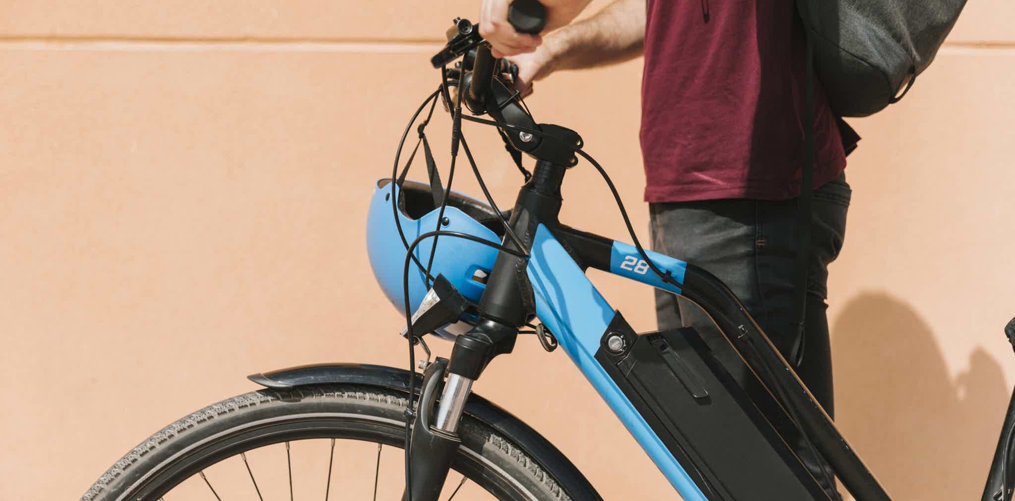 Imagen de archivo de una persona sujetando el manillar de una bicicleta eléctrica con sus dos manos.