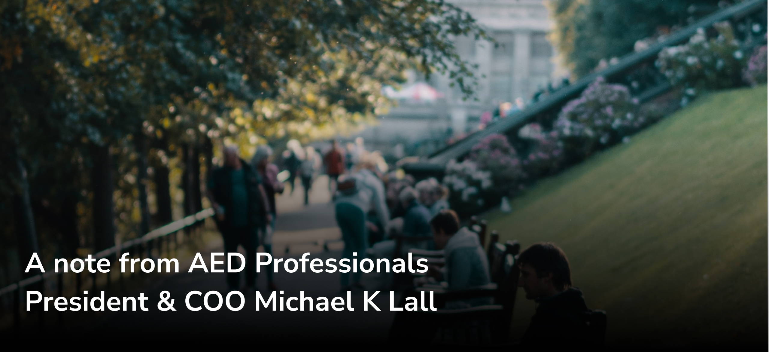 Image of people walking in a park with "A note from AED Professionals President & COO Michael K Lall"