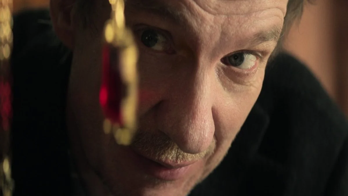 A close up shot of Doctor Destiny holding a chain in front of his face.