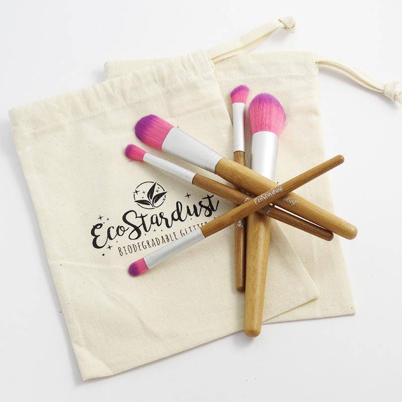 Picture shows multiple vegan bamboo makeup brushes arranged in a star shape, sitting on a cloth carry bag