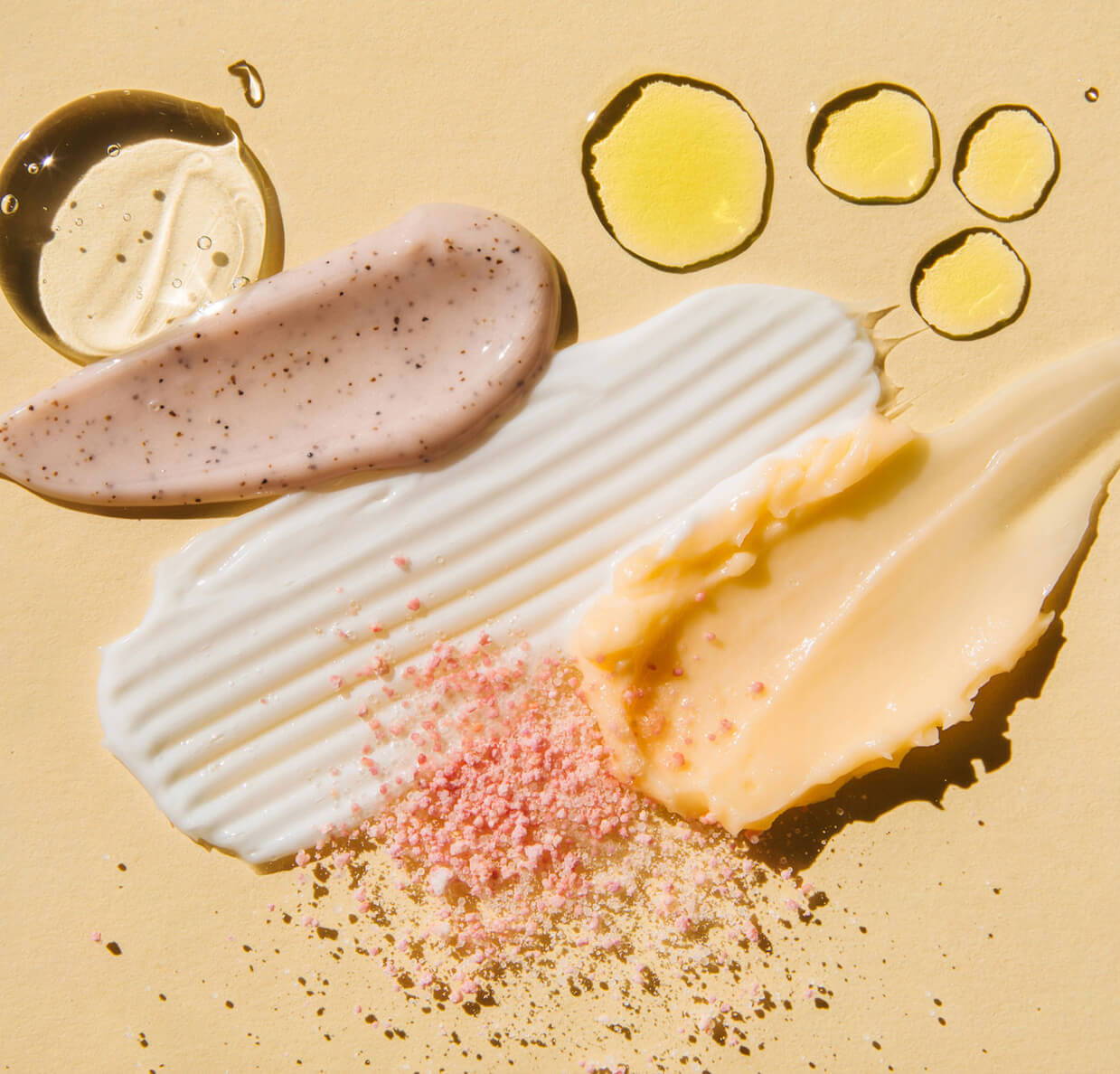multiple different skincare product goops and drops on a peach background