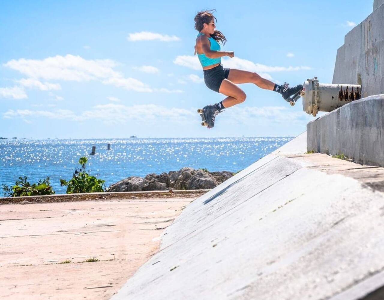Michelle on roller skates jumping on a concrete ledge
