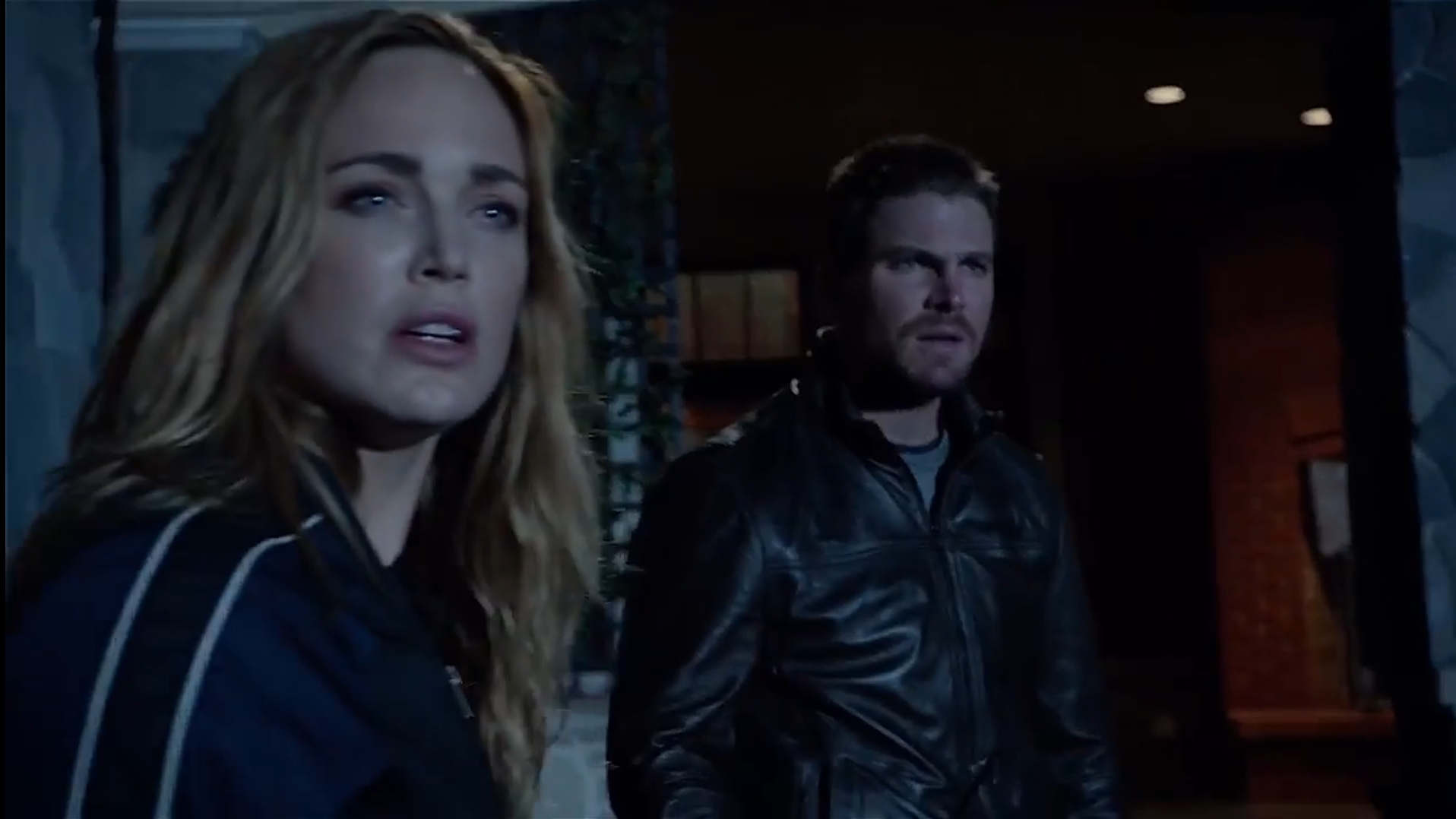 Sarah Lance and Oliver Queen with surprised expressions looking at someone off screen.