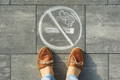 Photo of female-feet-with-picture no smoking painted on the ground