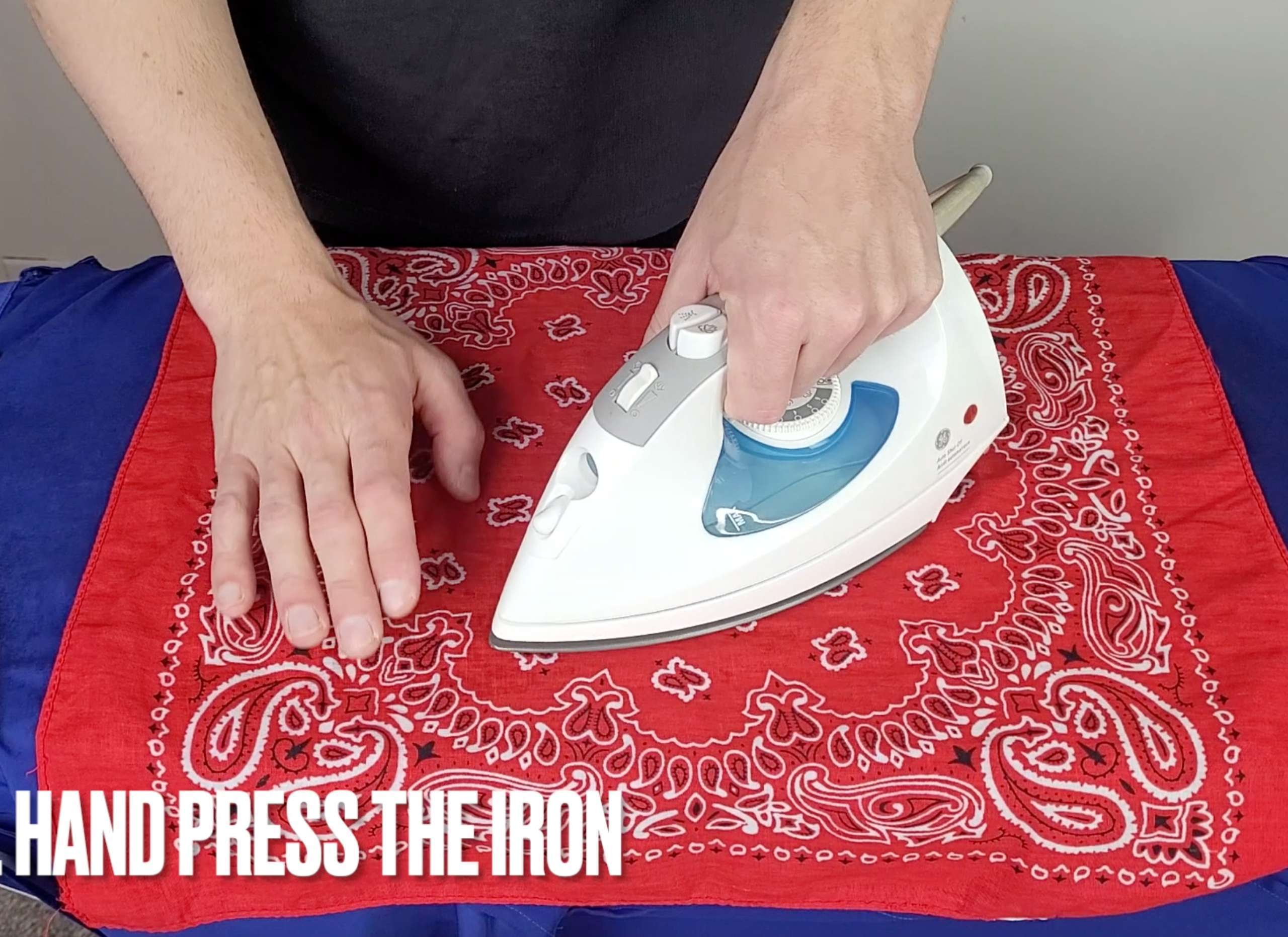 picture of a man holding an iron and hand pressing it onto a press cloth which is over top of silk pajamas