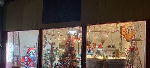 Festive shop window with a decorated Christmas tree, twinkling lights, and an "OPEN" sign, evoking holiday joy and warmth.