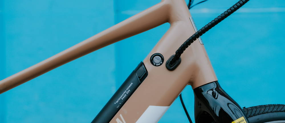 the front frame and battery on a tan aventon pace electric city bike