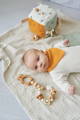 Baby lying on a soft blanket with wooden sensory toys - Montessori toy for newborn 0-3 months