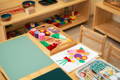 Montessori classroom with wooden furniture, toys, and educational materials.
