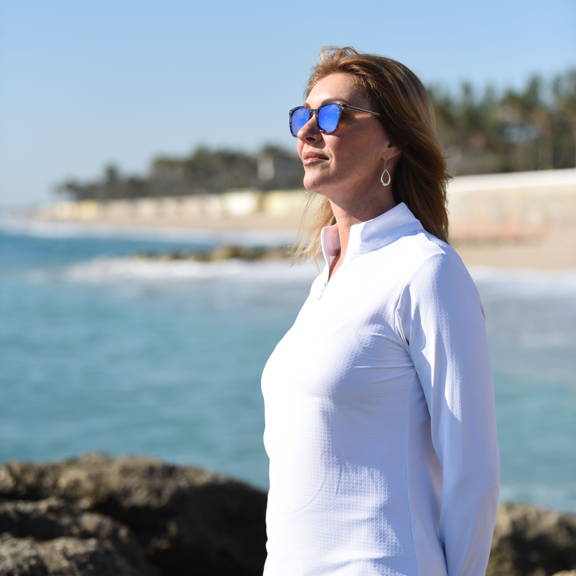 Val wears a white sun shirt while reflecting into the distance.