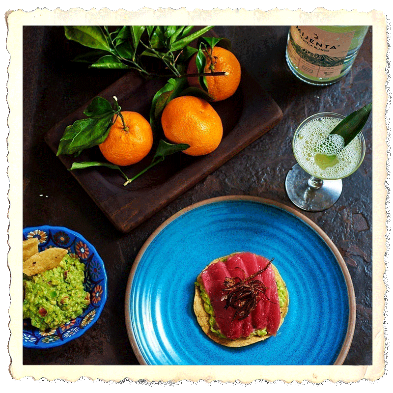 Closeup of tostada, guatemala, tequila cocktail, wooden board with tangerines and bottle of Mijenta Tequila Blanco