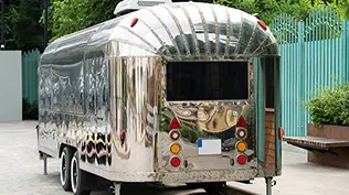 Photo d'un caravane rétro futuriste en métal argenté se tenant debout par une journée d'été pour un mariage.