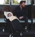 a father next to a baby in fellhof classic sheepskin footmuff in black with honey lambskin.