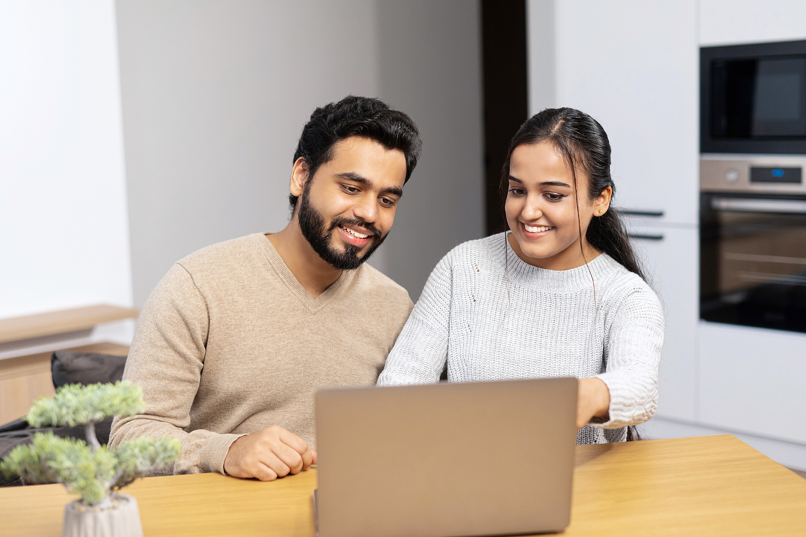 Cute middle eastern couple enjoys leisure time at home with a laptop.