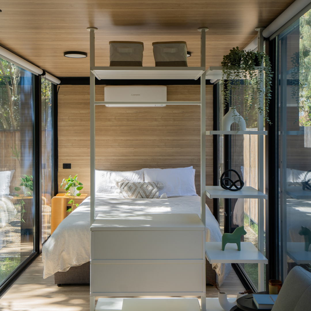 Bedroom inside the Byron Bay Elsewhere Pod featuring floor-to-ceiling glass, minimalist decor.