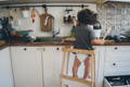 Kid in a learning tower in the kitchen.