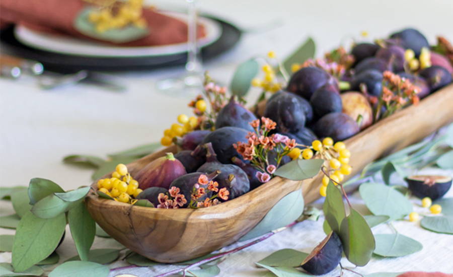 A centerpiece filled with figs, berries, and greenery