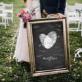 couple holding framed wedding guest book alternative with signatures