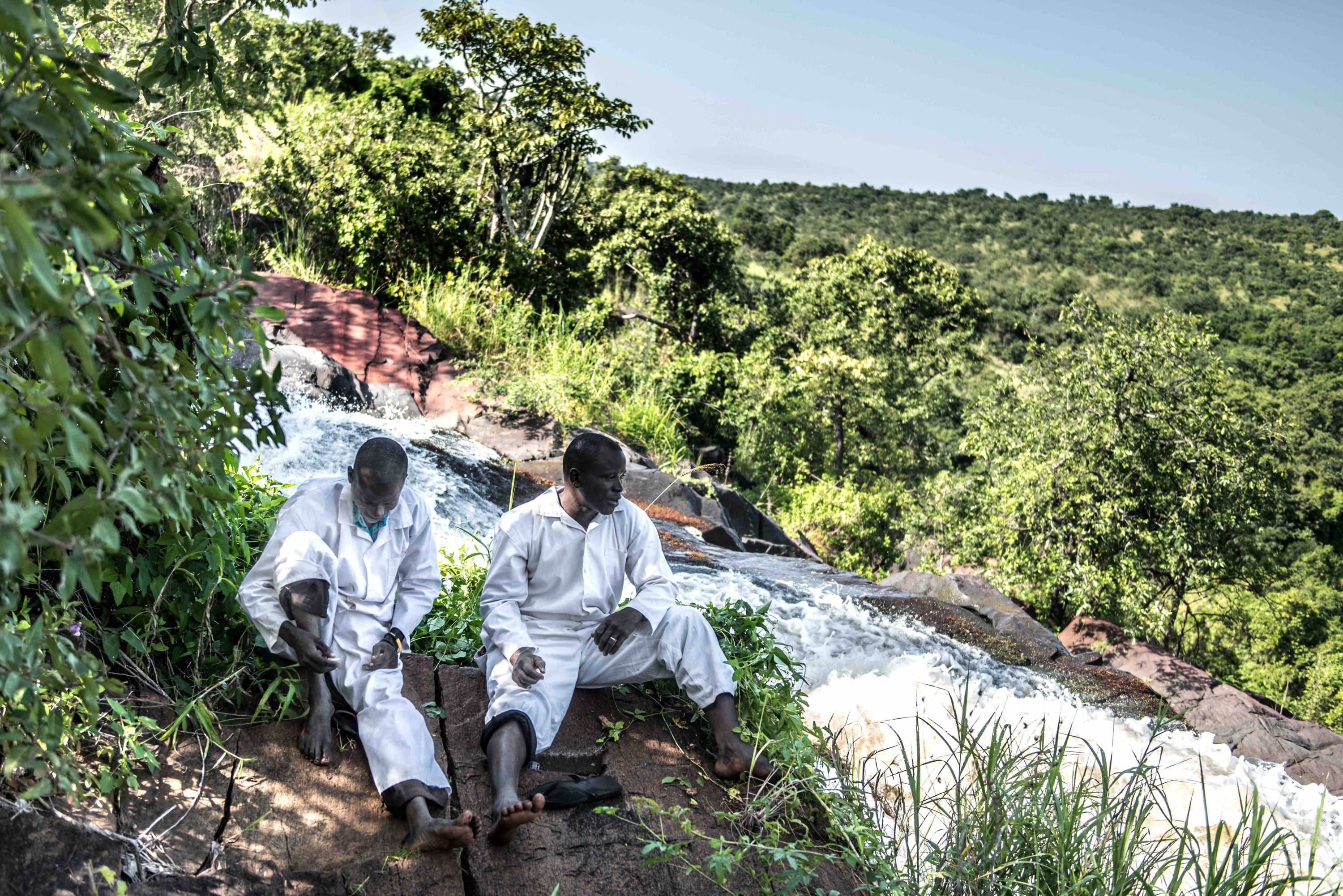 Members of a team assigned to capture black flies as part of a river blindness elimination program wait at their usual collecting spot at Aruu falls on the Agongo river