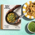 A book title 'Simply West African' sits on a colorful backlash next to a bowl of food and spices.