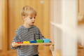 Little boy holding a wooden Montessori toy. 