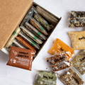 A cardboard box hold many plastic spice pouches meant for refilling you glass spice jars from Gneiss Spice