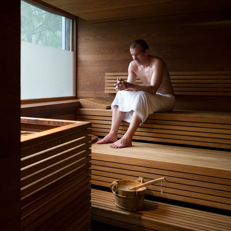 Mann mit Handtuch sitzt in der Sauna