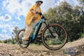 Femme cycliste sur son VTT electrique sur un chemin entouré d'arbres