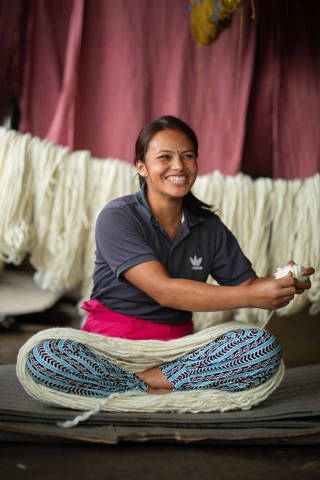 Artisan smiling while preparing wool roving.