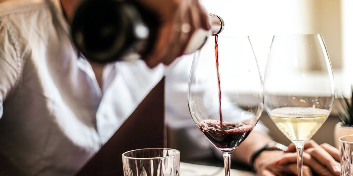 Man pouring red wine into a glass highlighting the importance of vision during tasting wine.