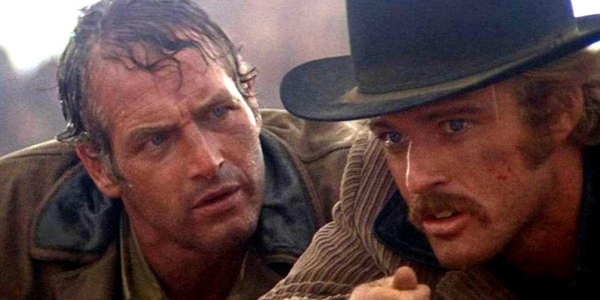 Butch and Sundance in the middle of a shootout laying on the ground looking at eachother.