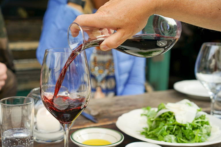 Savoury type of wine portrayed by a glass being filled by carafe of southern french red.