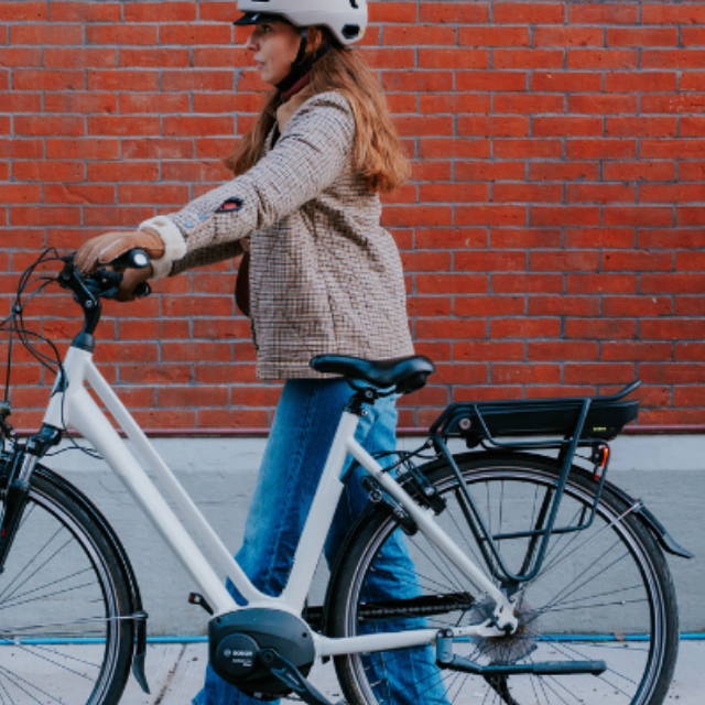 a woman walking her electric city bike