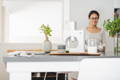 Cuzen Matcha Maker on a table in a dinning table. a woman is enjoying her matcha in the back.