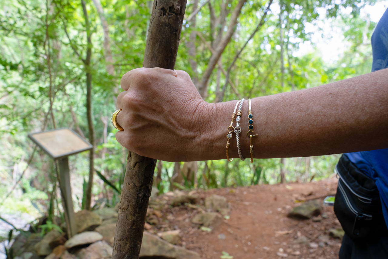 Hand with Vibe Jewelry holding a stick and walking along the Reef Bay Trail.