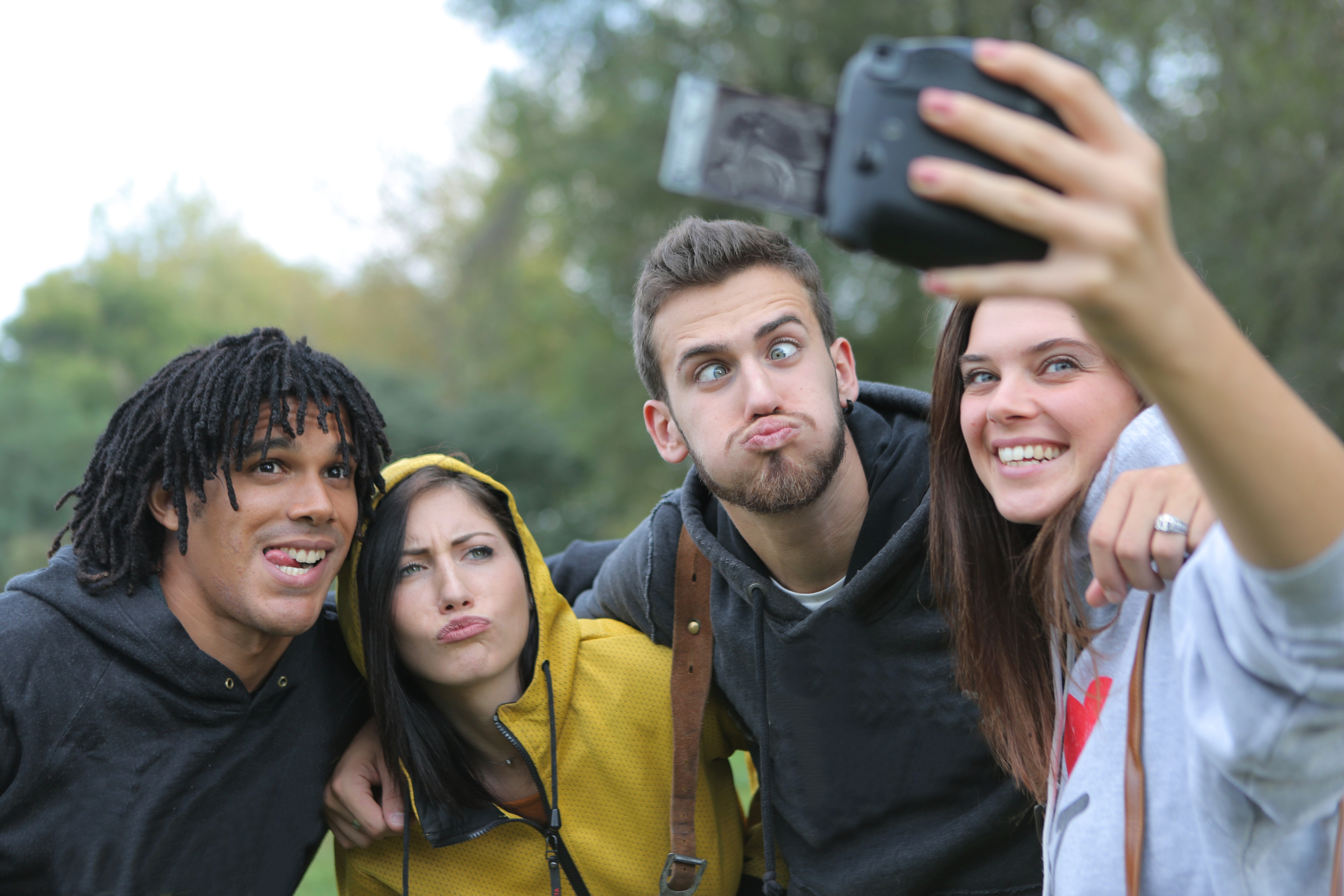A group of attractive multi ethnic friends make funny faces for someone taking a selfie.