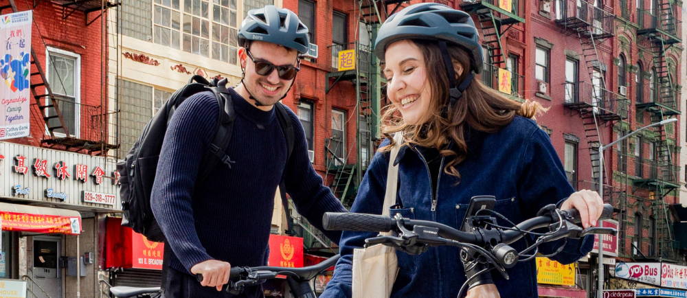 a man and woman riding electric bikes in chinatown