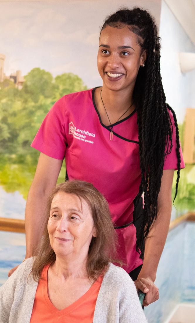 Larchfield care worker assists a resident in a wheelchair