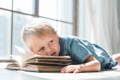 Little boy lying on a book.