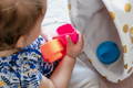 Baby holding stacking cups during sensory play for babies to build fine motor skills