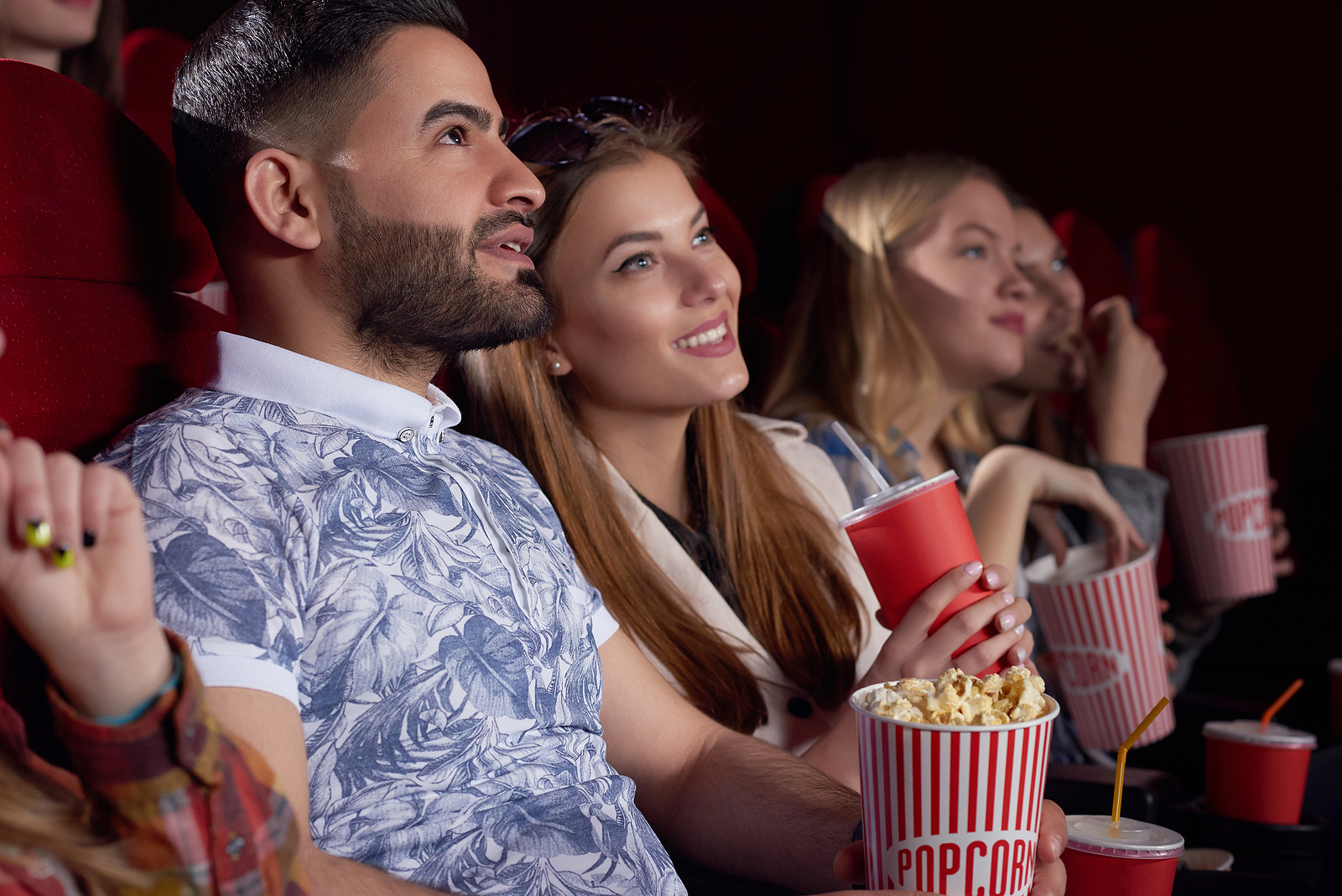 Couple watching a movie together smiling together with popcorn.