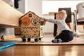 Little boy playing with a busy board wooden house.