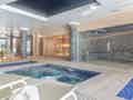 Ein moderner Indoor-Wellnessbereich mit sprudelndem Whirlpool, Sauna, Dampfbad mit Mosaikfliesen, Liegestühlen und stimmungsvoller Beleuchtung.