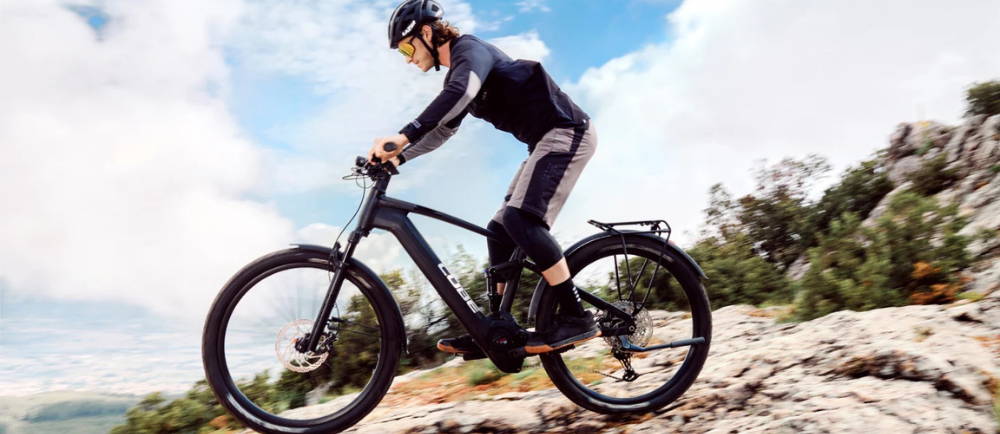 Male mountain biker riding a Cube E-MTB over some rocks