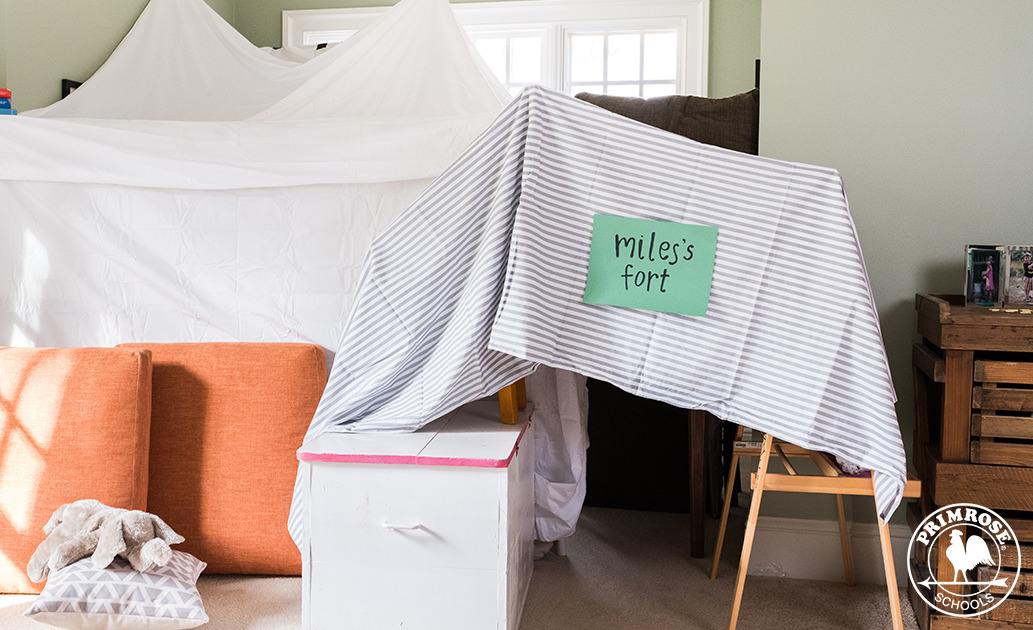 Indoor fort made with bed sheets and furniture labelled "Miles's fort"